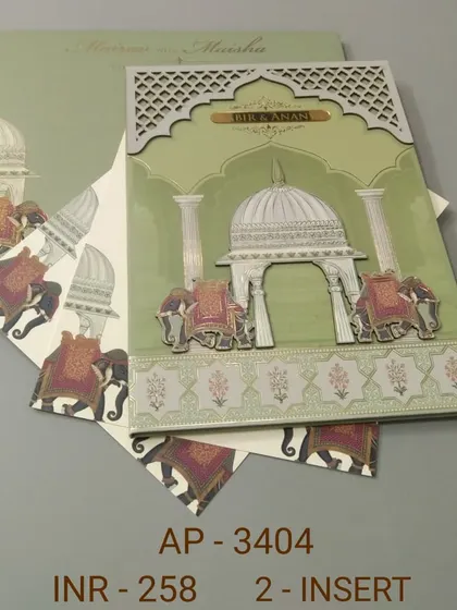 This sage green invitation showcases a grand palace dome flanked by decorated elephants, all with raised printing and silver foil. The matching inserts continue the elephant motif for a coordinated wedding stationery suite.