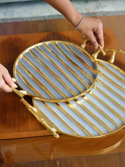 A pair of our round trays with a striking grey and gold stripe pattern and branch-like handles. These modern and artistic trays are designed to make a statement.