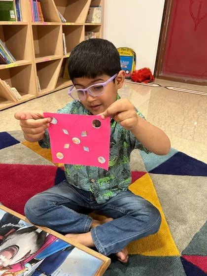 A student proudly displays his shape-based artwork from our spring camp. We explore different art techniques in every camp.