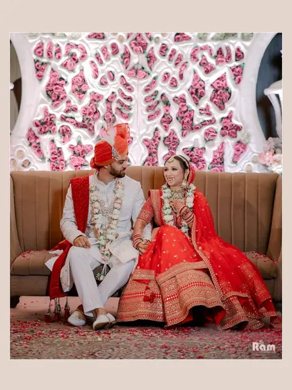 A classic portrait of the couple seated on a sofa after their wedding ceremony, holding hands and looking at each other with love.