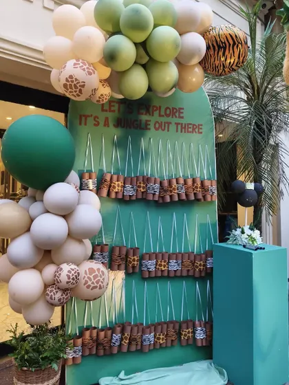 A creative party favor display for the jungle theme, with gifts wrapped in animal prints and arranged on a custom-built stand that reads 'Let's Explore, It's a Jungle Out There'.