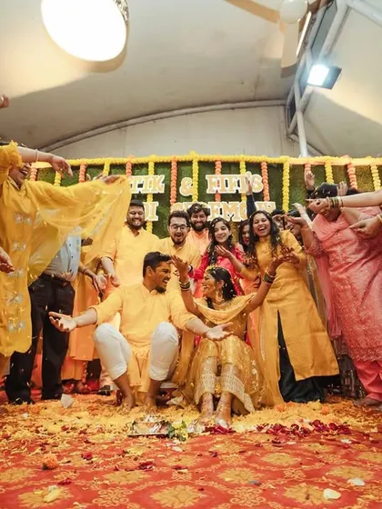 The family surrounds the couple, showering them with blessings and flowers after the Haldi ritual.