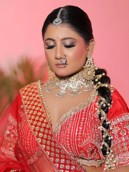 The complete look against a soft pink background. The red lehenga stands out beautifully, and the makeup perfectly complements the entire aesthetic.