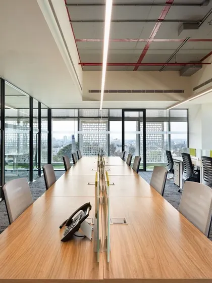 An open-plan office layout at CorporatEdge, Bangalore, designed to maximize natural light and exterior views. The arrangement of desks alongside the windows creates a pleasant and energizing work environment for employees.