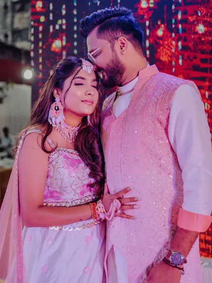 A Haldi bride and groom, her hair in a simple half-updo with soft waves.