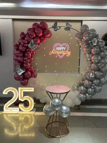 A centered view of the silver jubilee decoration, highlighting the butterfly accents on the balloon arch and the glowing "Happy Anniversary" sign.