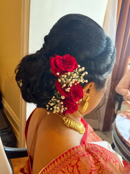 A hairstyle can complete the entire look. I created this beautiful messy bun using the client's own hair and adorned it with fresh red roses and baby's breath for a romantic and traditional touch.