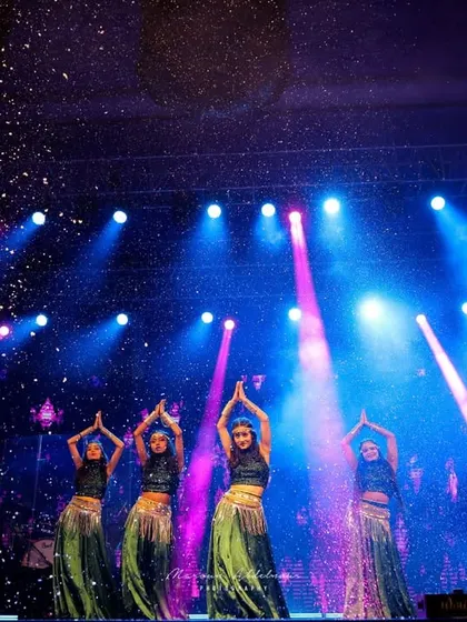 Dancers perform on the 'Cosmic Rhythm' sangeet stage, with dramatic lighting and a starry confetti effect creating a mesmerizing visual.
