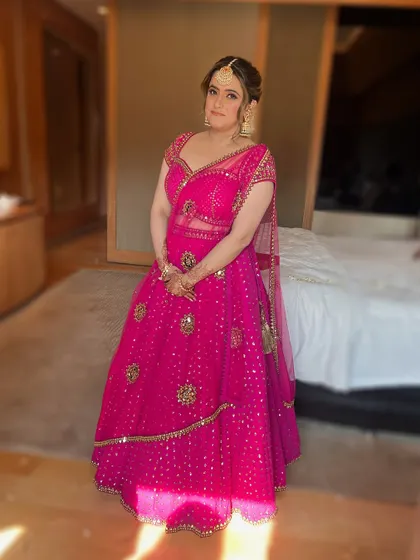 A full-length shot of the bride at her Mehendi, looking radiant in a vibrant pink lehenga.