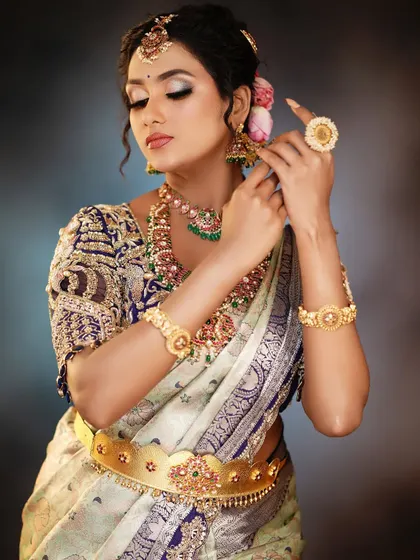 This bridal look features a beautiful contrast between the light-colored saree and the dark, embroidered blouse.