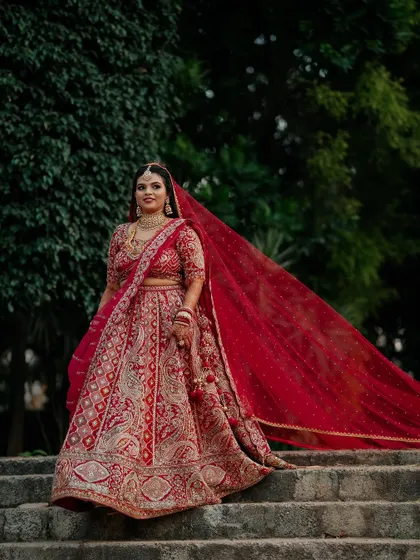 A regal bride in her magnificent red lehenga. We capture the grandeur of the bridal attire, creating portraits that are both powerful and elegant.