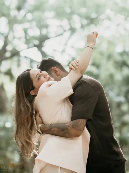 A candid and spontaneous moment of a couple embracing in the woods. The woman's joyful expression looking back at the camera makes this a lively and engaging portrait.