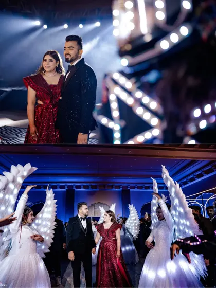 Jatin and Muskan's grand entrance, flanked by performers with illuminated angel wings. This collage captures the spectacular and magical start to their Sangeet celebration.