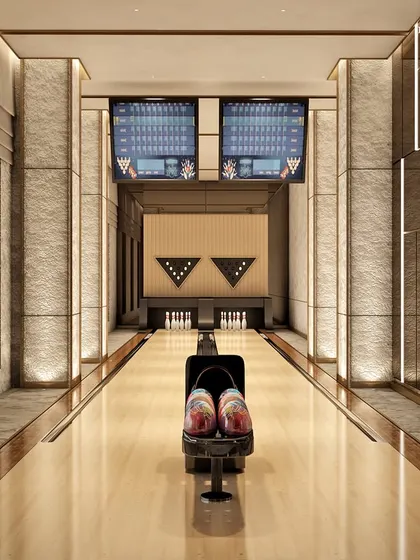 A state-of-the-art bowling alley with stunning city views. The design integrates modern aesthetics with practical luxury, using a harmonious blend of stone, metal, and wood to create a visually stunning and functional entertainment space.