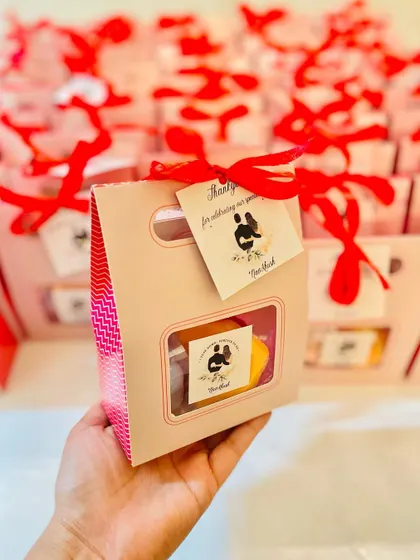 These anniversary return favors for "NavKhush" are packaged in a pink and red box, celebrating the couple's special day.