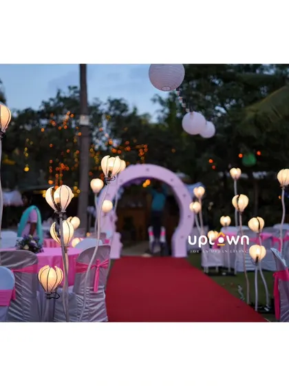 Unique lotus-shaped lights lining the aisle for an outdoor event.