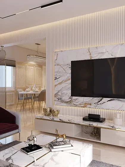A render of a high-end apartment living room where white marble, fluted walls, and deep red accent chairs come together to create an opulent and stylish entertaining space.