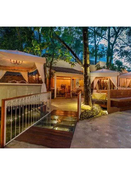 A wider view of the outdoor seating area, showing how the cabanas are nestled amongst the trees, creating a sense of being in a lush garden.