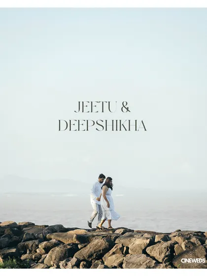 A stunning wide-angle pre-wedding shot of a couple walking on coastal rocks against a vast, open sky, creating a feeling of freedom and endless possibilities.