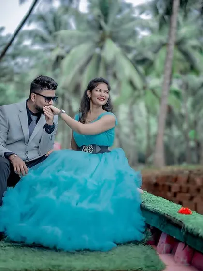A romantic pre-wedding moment on a boat. The groom-to-be kisses his partner's hand, who looks radiant in a sky-blue ruffled gown.