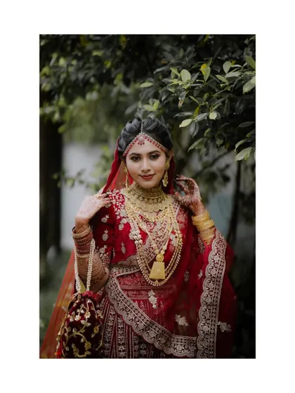 A stunning portrait of a bride in a rich red lehenga, her regal pose and intricate jewelry creating a look of timeless elegance.