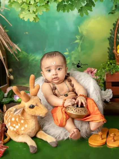 A regal pose from our little Lord Ram, sitting with his deer friend in a lush green backdrop.