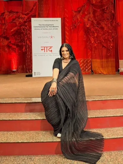 A dramatic pose on the steps of the event stage. The long pallu of the pleated saree creates beautiful lines and movement.