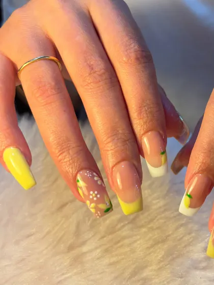 A fresh and zesty summer design. This set features a lemon-themed French manicure with hand-painted lemons and delicate white flowers on a sunny yellow base.