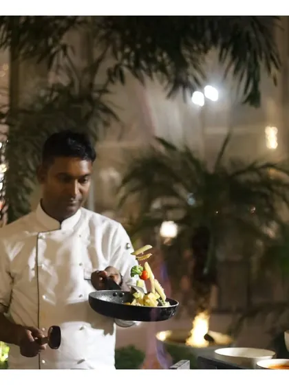 A chef meticulously plating a dish at an outdoor event, showcasing the fine-dining level of detail we bring to every plate.