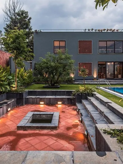 The outdoor leisure zone of The Grey Grotto, featuring a sunken lounge with a fireplace, tiered seating, and a swimming pool. This space was designed as a central gathering point for family and social events.