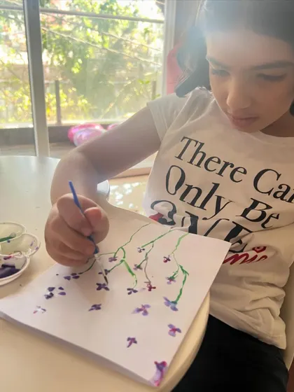 Deep in concentration, this young artist is carefully adding purple blossoms to her painting. It's a joy to watch their skills develop with each session.