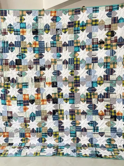A Sawtooth Star memory quilt made from 15 of a client's husband's shirts. This custom design combines a traditional pattern with personal materials for a truly special keepsake.