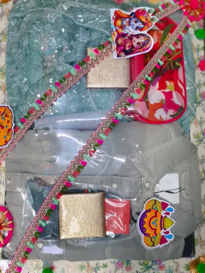 A colorful Holi hamper with clothes for a couple, along with gulal and other festive items. The packing is decorated with bright, multicolored lace.