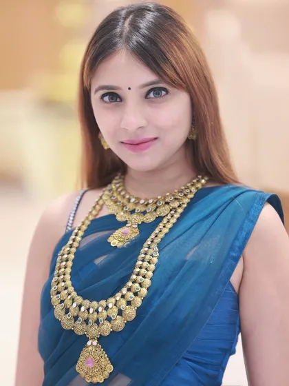 A direct-to-camera portrait, perfect for showcasing the intricate details of the layered gold necklaces.
