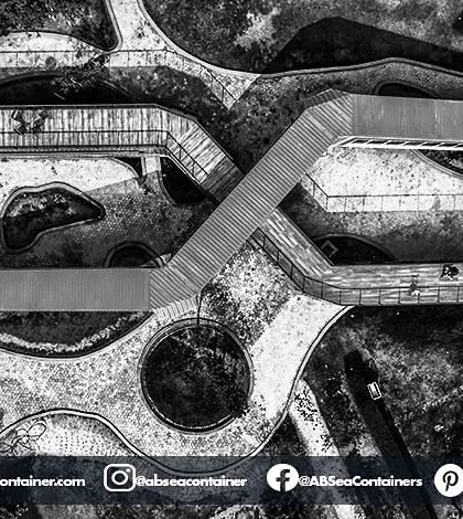 A black and white aerial view of 'Cafe Infinity' emphasizes the geometric forms and structural layout of the project. The interlocking containers create a unique architectural footprint.