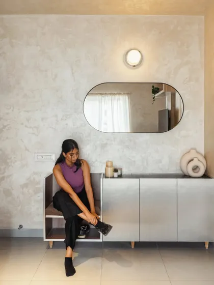 The entryway features a custom-designed console with an integrated seat for putting on shoes. This small but thoughtful detail adds functionality to the space, keeping it organized and welcoming. The textured wall finish and organic-shaped mirror add a touch of warmth and style.