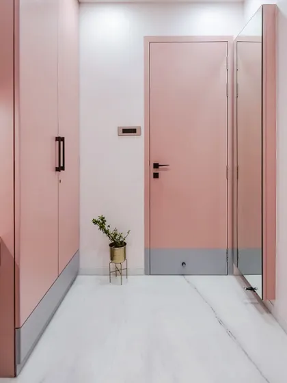 This view highlights the clean, minimalist aesthetic of the pink room, with handleless wardrobe doors and a simple, full-length mirror. The two-tone effect on the door and wardrobe base adds a subtle, modern design detail.