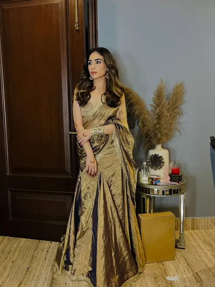 A self-designed gold tissue saree. The fabric has a beautiful sheen that catches the light, making it perfect for an evening wedding reception or a formal event.