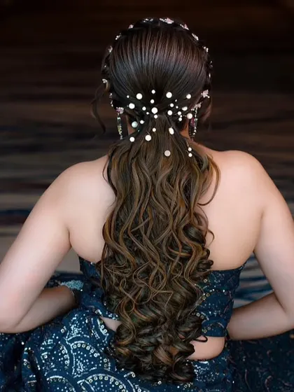 A stunning open hairstyle with soft curls and pearl accessories. This is a romantic and dreamy look, perfect for an engagement or reception.
