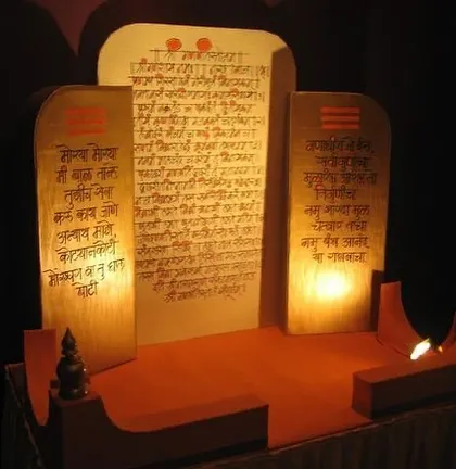 A custom-made throne for a Ganpati idol, designed to look like ancient scrolls with handwritten shlokas. The warm backlighting creates a divine glow, making it a unique and reverent centerpiece.