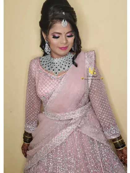 A full-length view of Shruthi's stunning reception outfit. The soft pink lehenga with intricate silver work pairs beautifully with the glamorous makeup and hairstyle, creating a cohesive and elegant look.