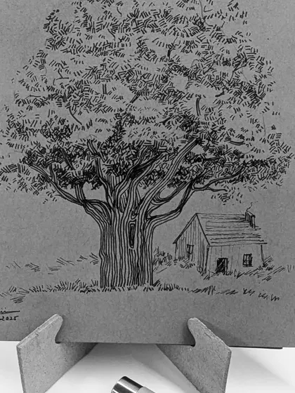 The completed tree and hut ink drawing, displayed on a small easel.