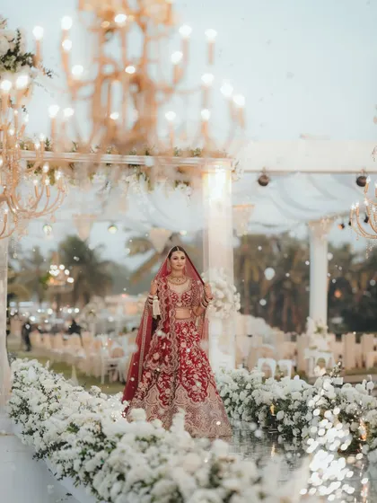 The bride's stunning entry down the mirrored aisle, lined with white flowers and chandeliers. A true fairytale moment.