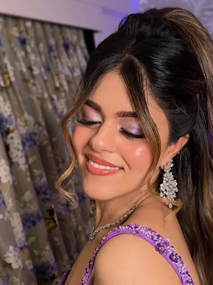 Glass skin glamour for a cocktail event. This look features a shimmery lilac eyeshadow and a high, wavy ponytail for a fun and stylish party look.