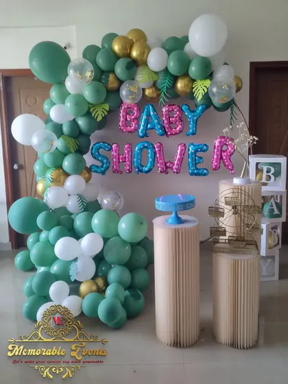 A jungle-themed baby shower decoration with green and gold balloons, tropical leaf accents, and 'BABY SHOWER' foil letters.