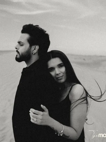 A beautiful black and white embrace in the desert. She rests her head on his back, looking at the camera with a gentle expression, creating a portrait that is both intimate and engaging.