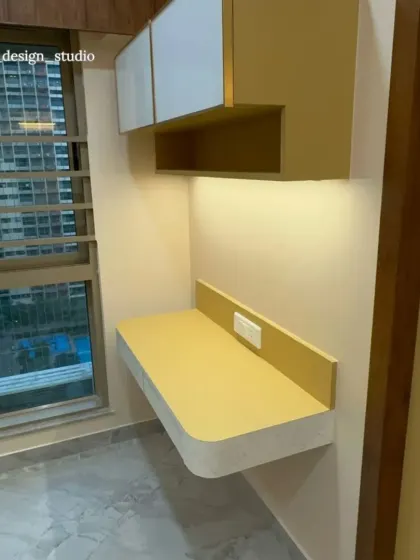 We carved out a compact study or vanity nook in this bedroom, featuring a floating desk and overhead cabinets in the same mustard yellow. The under-cabinet light makes it a functional workspace with a view.