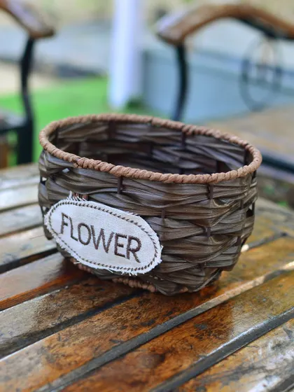 A simple, dark brown woven basket-style planter, perfect for holding flowers or small potted plants on a tabletop.