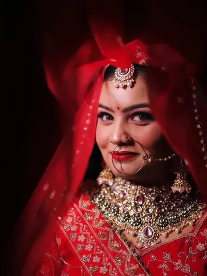 A close-up of Himanshi through her red veil. Her eyes and her beautiful smile shine through.