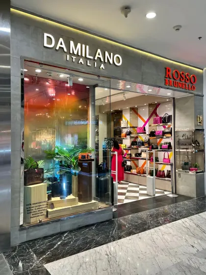 A close-up of the Da Milano side of the Chandigarh store, featuring a colorful, iridescent window film and a natural plant display.